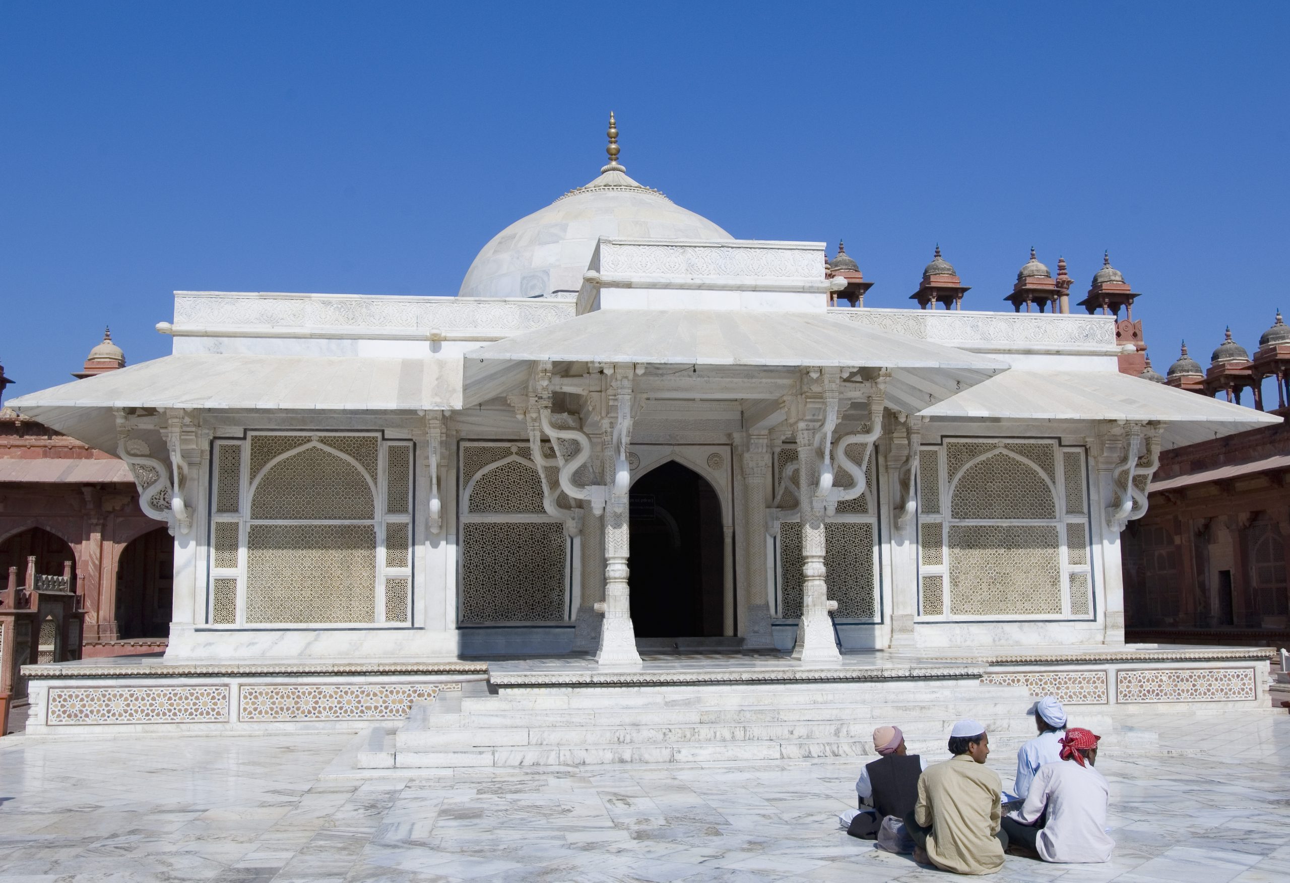 4 people sitting outside a mosque